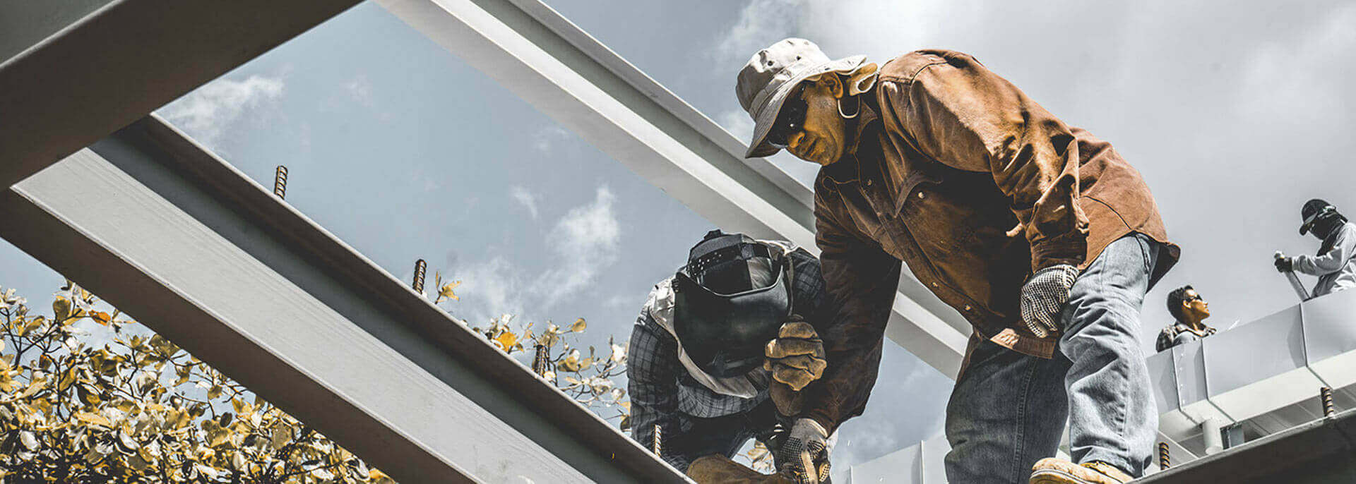 Soldadores de TM Industrial trabajando sobre una viga metálica contra el cielo