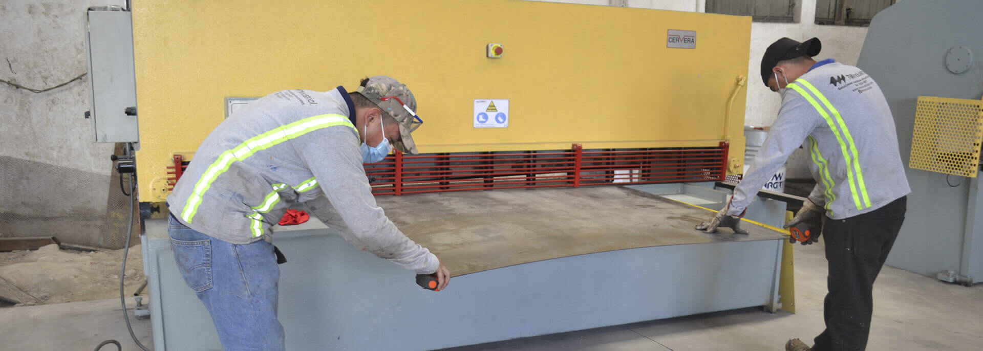 Operarios de TM Industrial cortando lámina en la guillotina del taller