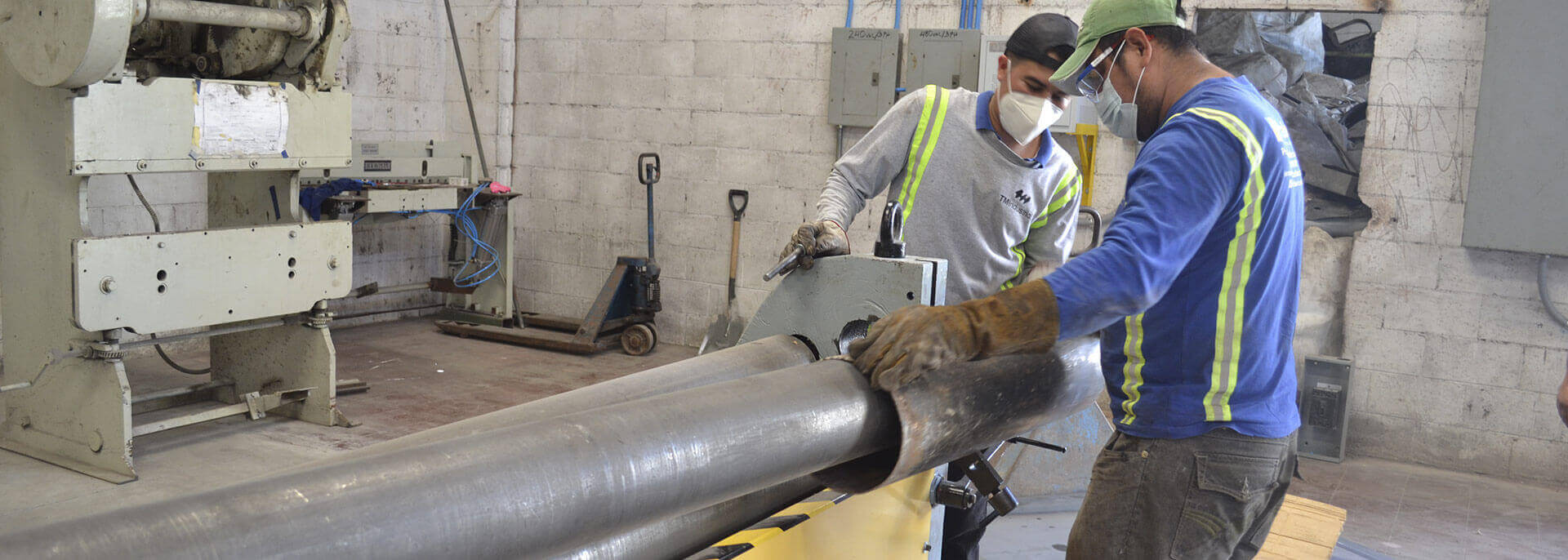 Operarios de TM Industrial enrollando en frío una lámina metálica cilíndrica